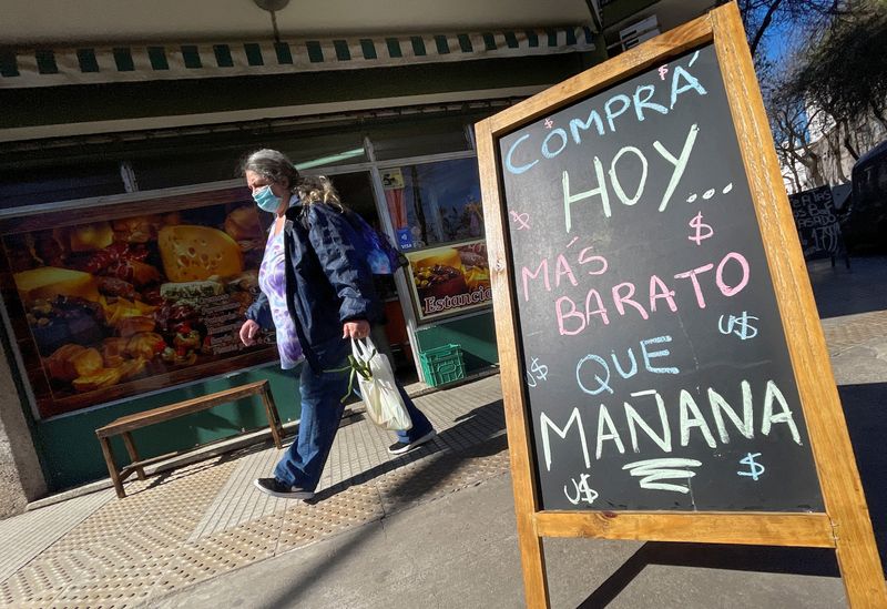 Una compradora pasa junto a un letrero que dice "Compre hoy, más barato que mañana" fuera de una tienda, en medio de una alta inflación y una crisis económica, en Buenos Aires